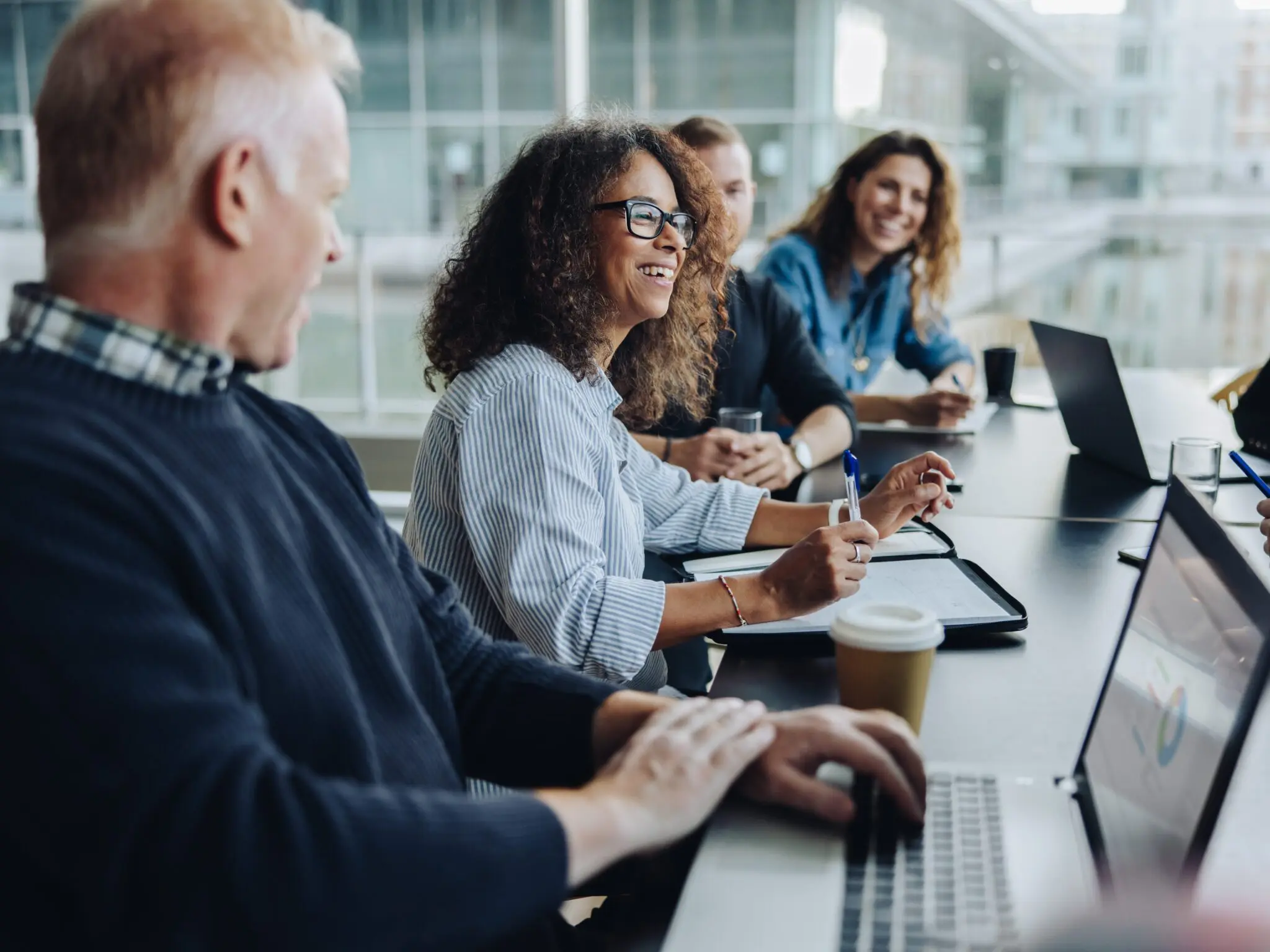 Multi-ethnic business people smiling during a meeting in conference room. Team of professionals having meeting in boardroom.