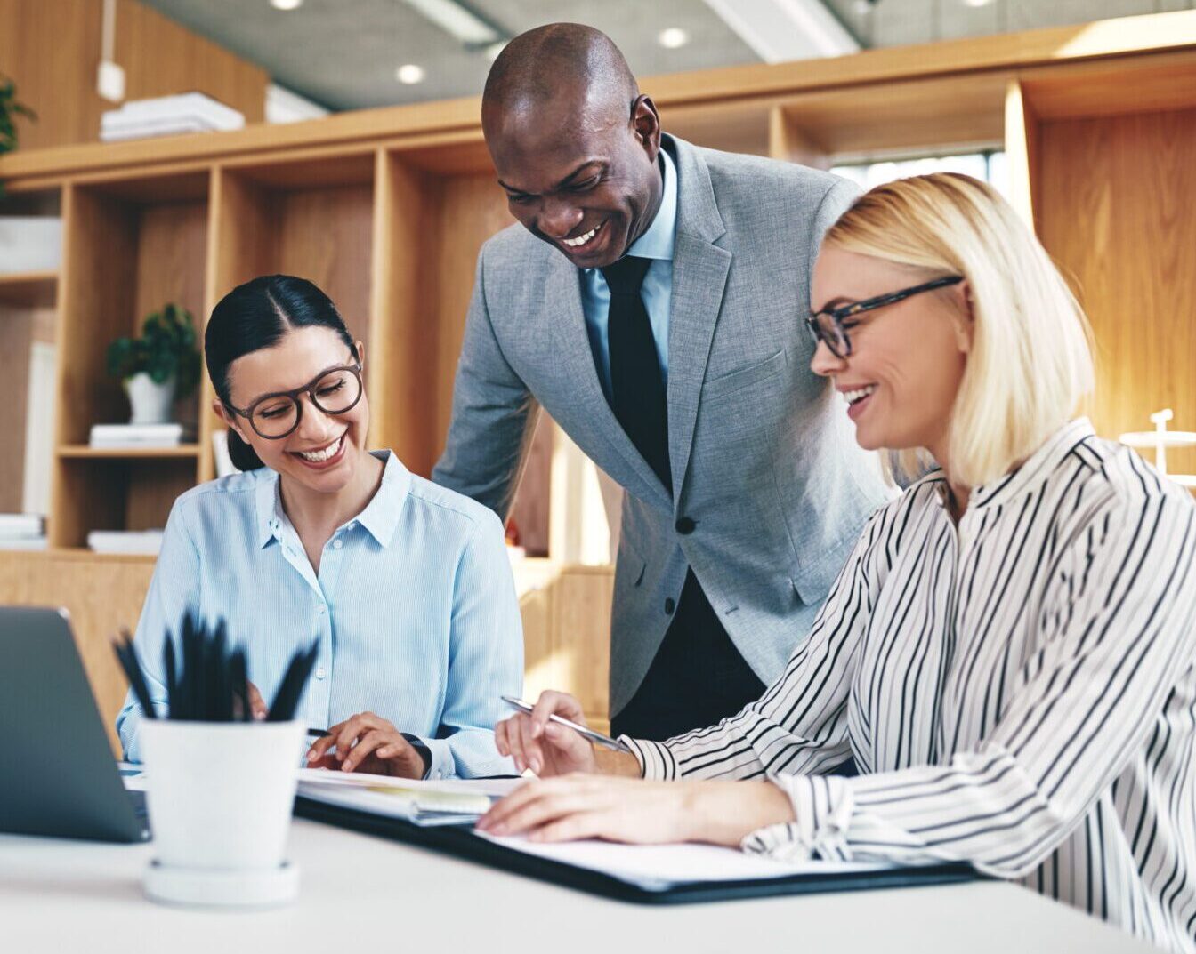 Diverse group of businesspeople laughing while having a meeting together around a table in an office